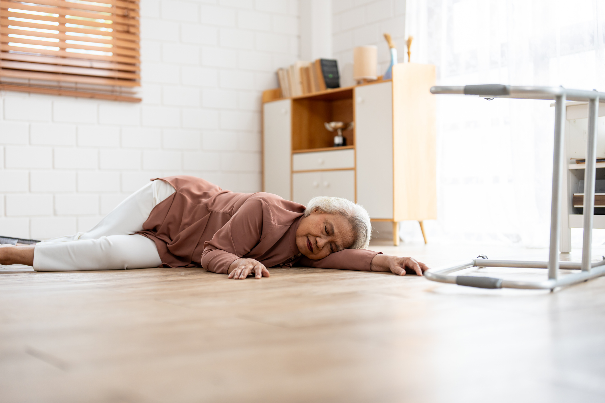 Asian senior elderly female fall on the ground while walk alone in house. Mature older grandmother having an accident and fainting while doing physical therapy after retirement in living room at home.